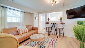 Un salon moderne avec un canapé en cuir, une table basse, un téléviseur et un coin repas comprenant des chaises et une table.