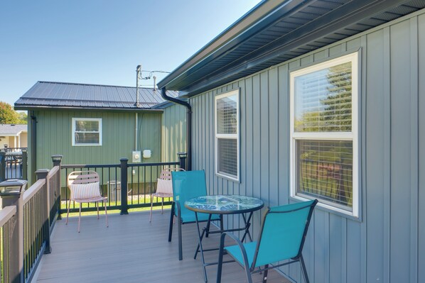 A covered outdoor area with a table and chairs, a railing, and a building with large windows. - 'blue Heron' Walk to Kelso Beach! Pet-friendly Gem (Erie)