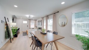A modern living room with a wooden dining table, black chairs, a sofa, and a large window with blinds. - 'zen Haven' Lakefront Erie Home w/ Shore Access (Erie)