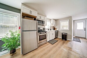 Una cocina moderna con electrodomésticos de acero inoxidable, armarios blancos y piso de madera.