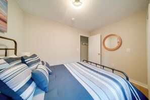 Una camera da letto con un letto, cuscini, uno specchio rotondo e una porta che dà su un'altra stanza.