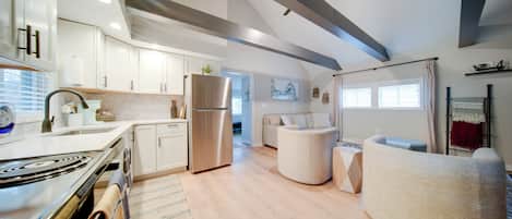 Una cocina moderna con estufa integrada, refrigerador de acero inoxidable y armarios blancos.