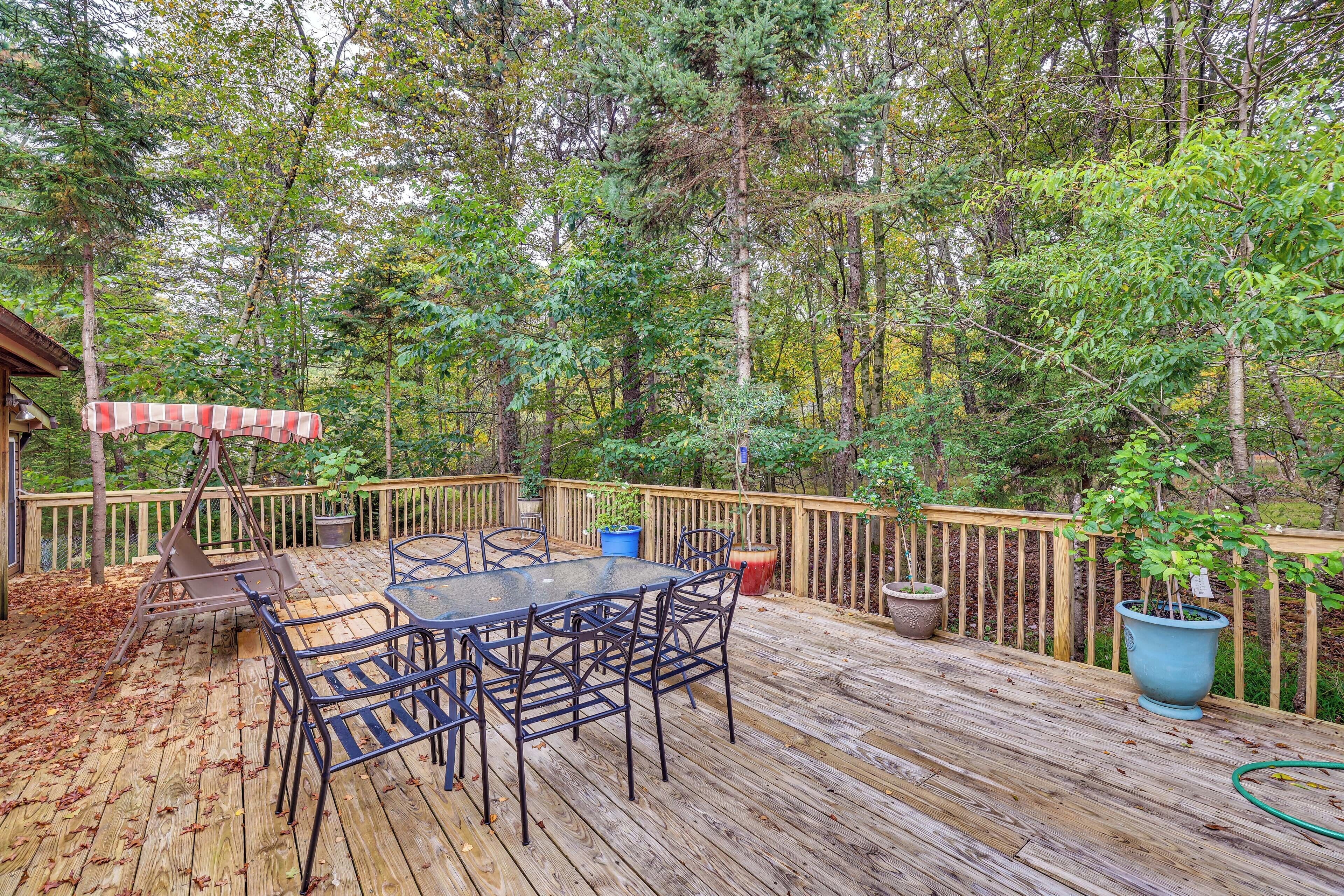 A wooden deck with a table and chairs, surrounded by trees.