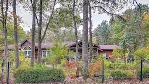 A lodge with multiple buildings, surrounded by tall trees and a well-maintained garden.