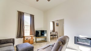 A living room with a TV, two sofas, a coffee table, and a dining area with a table and chairs. - Walkable Location, Fenced Yard: Wickenburg Home! (Wickenburg)