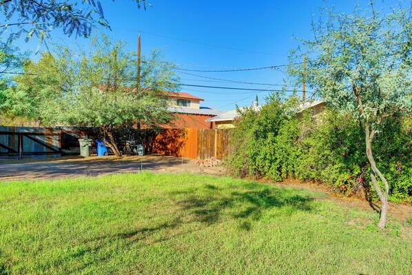 A residential backyard with a wooden fence, a tree, and a house with a red roof.