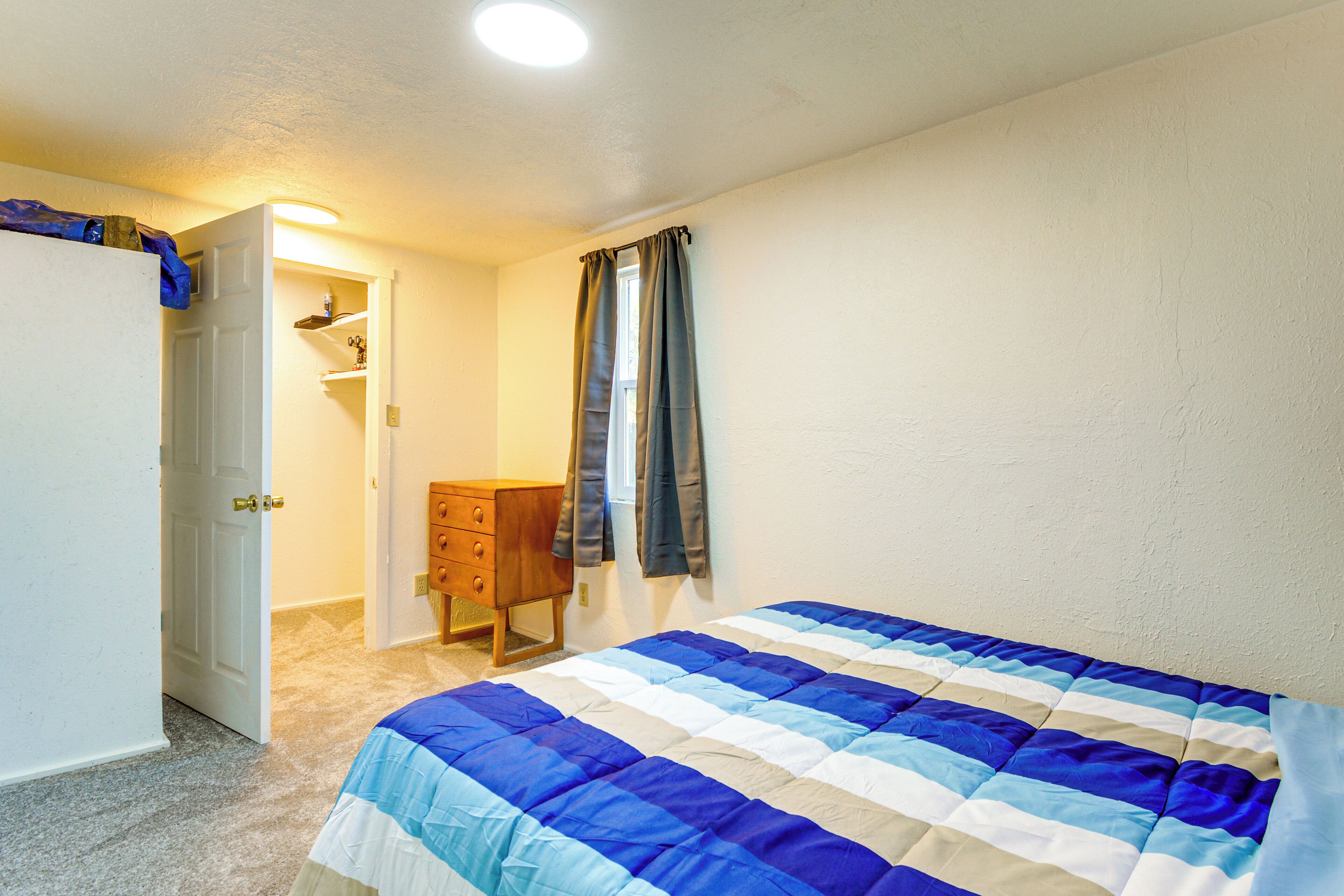 Een slaapkamer met een bed, een dressoir, een kledingkast en een deur naar een andere kamer.