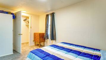 Een slaapkamer met een bed, een dressoir, een kledingkast en een deur naar een andere kamer.