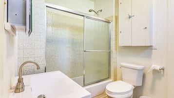 A bathroom with a shower, toilet, sink, and cabinets.
