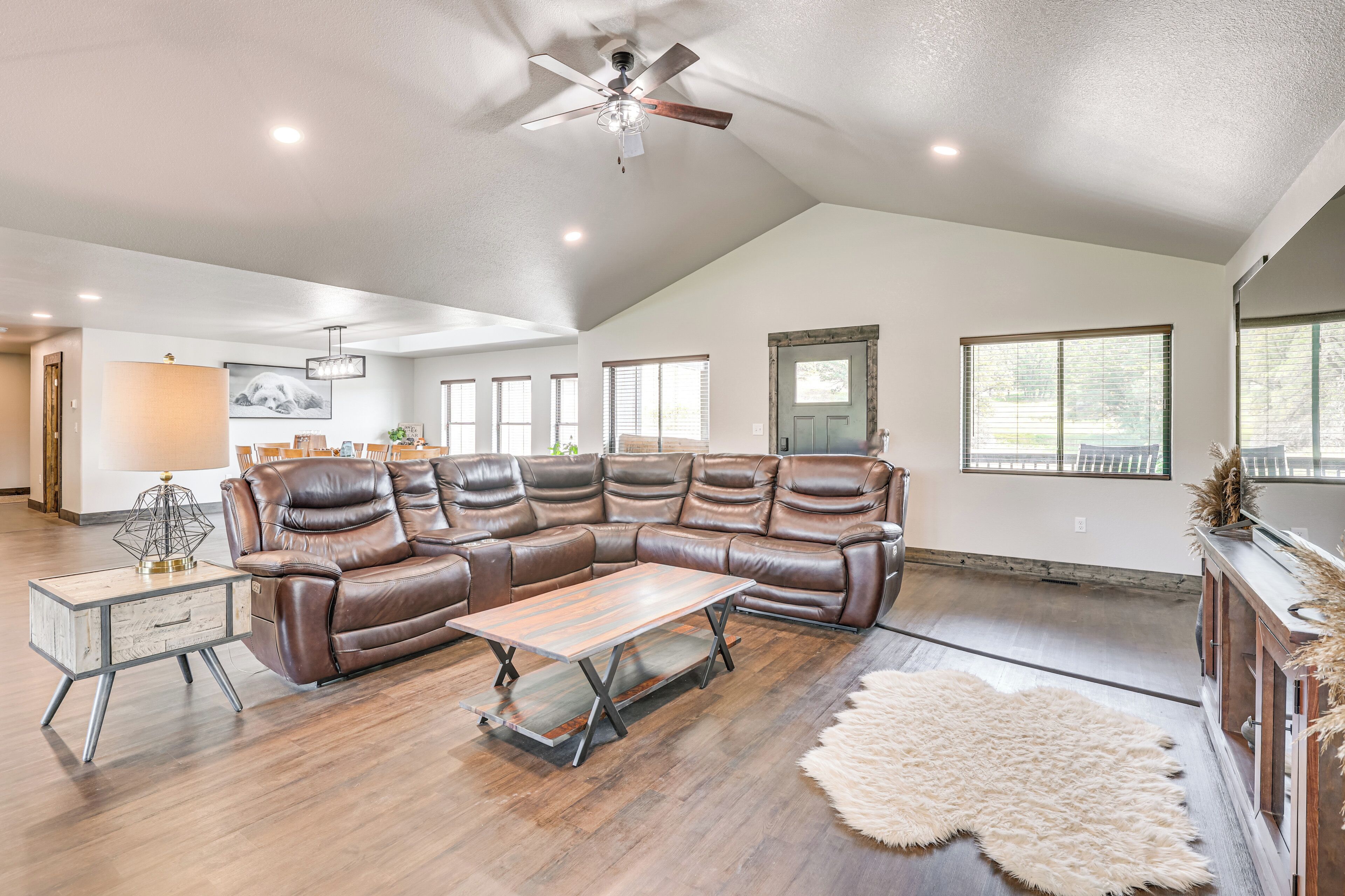 A spacious living room with a sectional sofa, a wooden coffee table, and a ceiling fan.