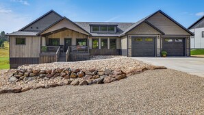 A modern two-story house with a stone foundation, a covered porch, and a garage. - Deck & Hot Tub: Group Golf Retreat in Sturgis (Sturgis)