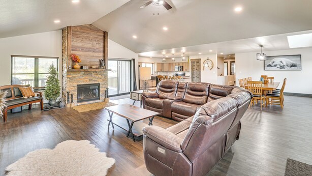 A spacious living room with a fireplace, leather sofa, and a dining area with wooden furniture. - Deck & Hot Tub: Group Golf Retreat in Sturgis (Sturgis)