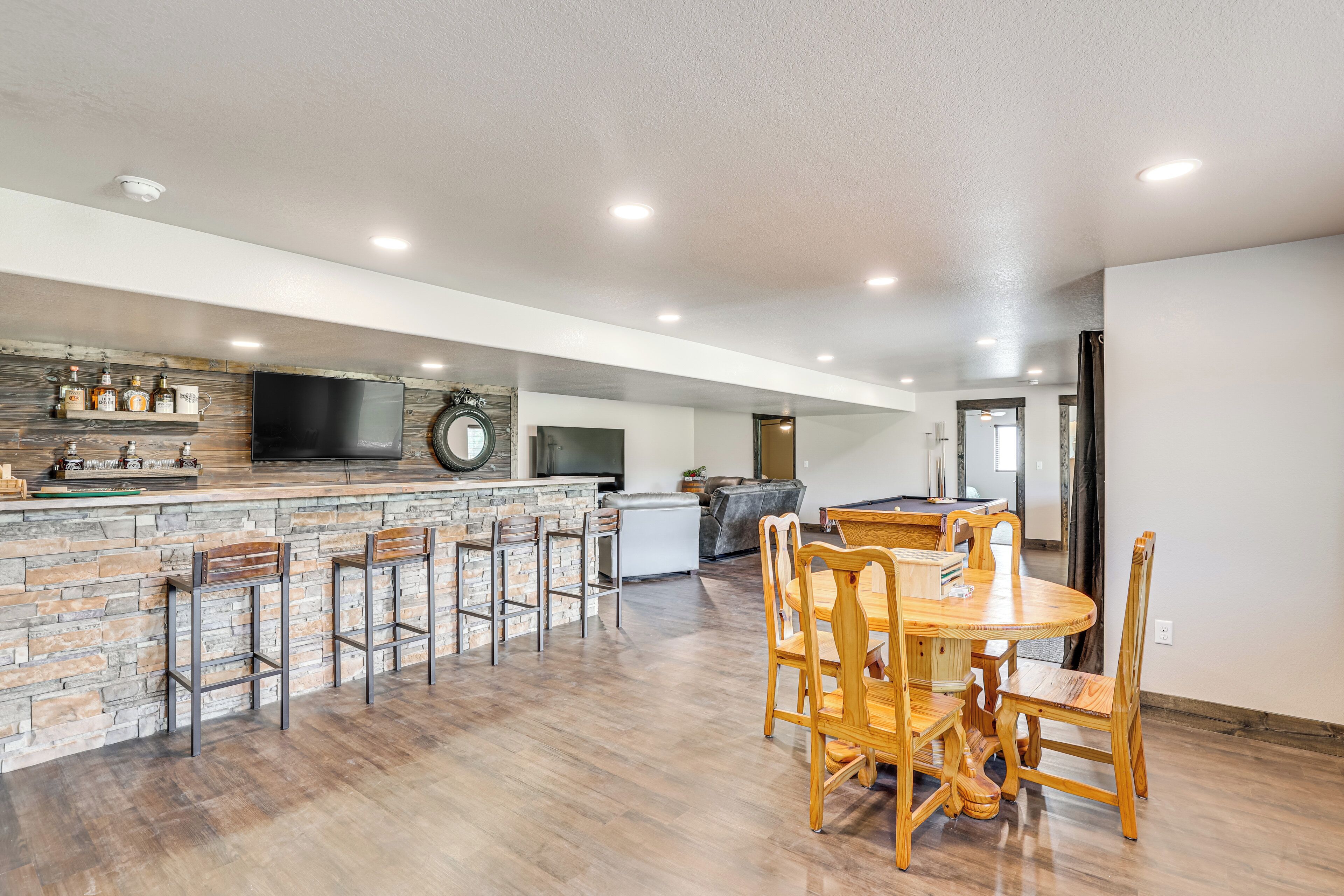A spacious kitchen with a stone countertop, a large TV, and a dining area with wooden chairs and a table.