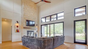 A spacious living room with a large sectional sofa, a fireplace, and a TV mounted on a stone wall. - Nat'l Forest Access & Mtn Views: Family Eagar Home (Eagar)