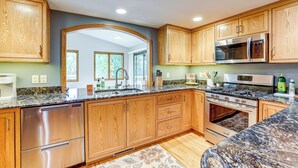 A kitchen with wooden cabinets, stainless steel appliances, granite countertops, and a large window. - Mississippi River Home 8 Mi to Dtwn St Cloud! (St Cloud)