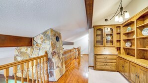 A wooden staircase with a stone accent wall, a wooden railing, and a wooden cabinet with glass doors. - Mississippi River Home 8 Mi to Dtwn St Cloud! (St Cloud)