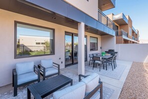 Eine Terrassenanlage im Freien mit Sitzgelegenheiten, einem Tisch und Grillbereich.