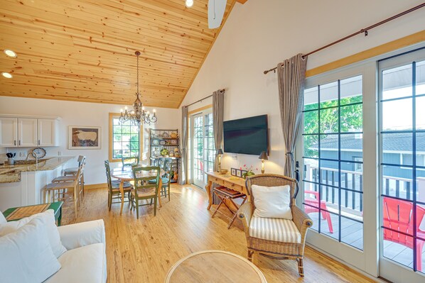 A spacious living area with a wooden ceiling, a dining table, and a large window with a view of the outdoors. - Walk to Dtwn Syracuse: Private Lake-view Home (Syracuse)