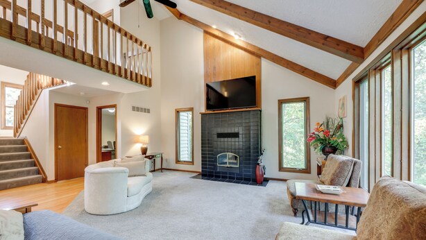 A spacious living room with a fireplace, a staircase, and large windows. - 4 Mi to Dtwn Loveland: Private Retreat w/ Decks (Loveland)