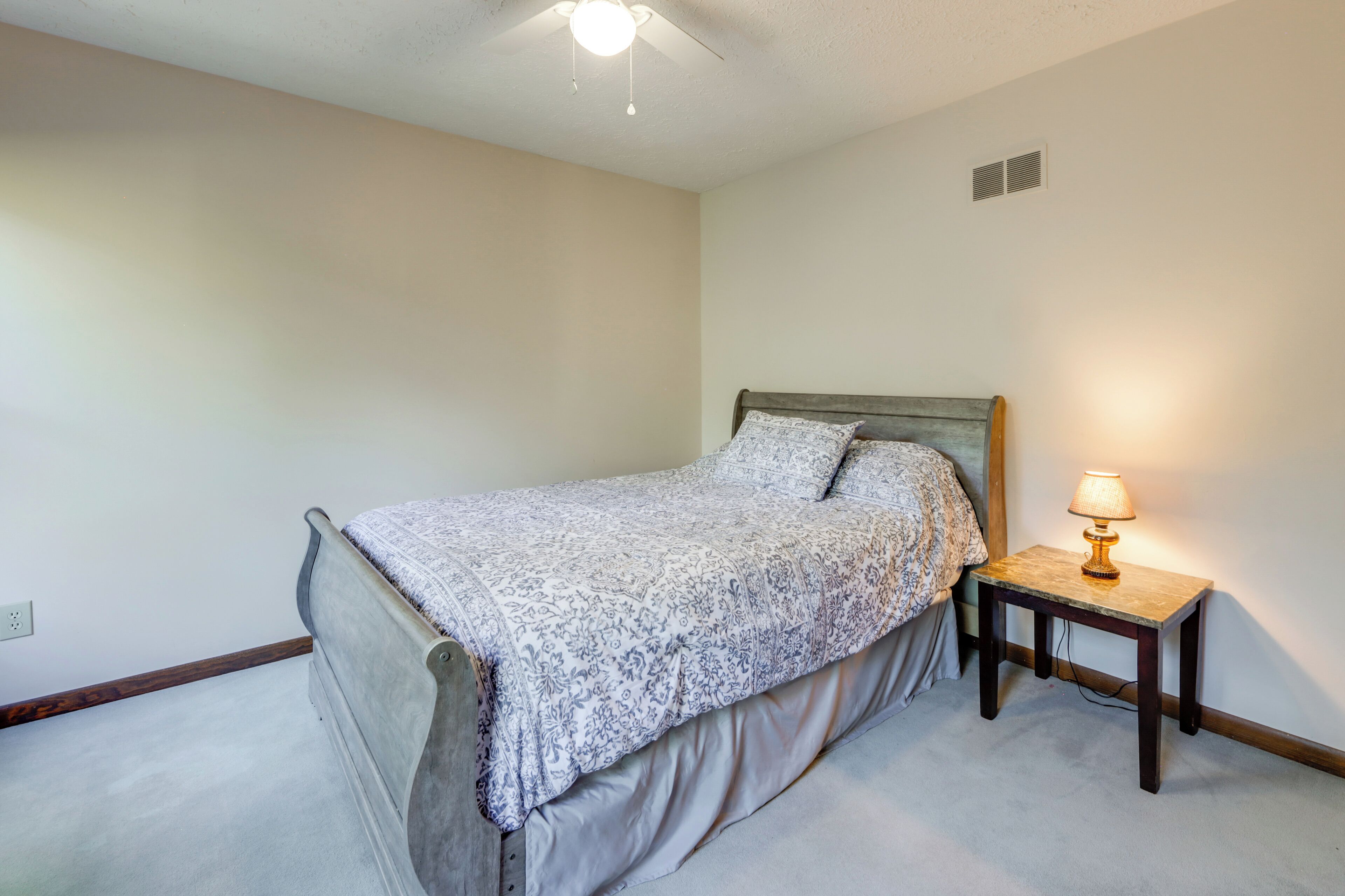 Une chambre à coucher avec un lit, une table de chevet et un ventilateur de plafond.