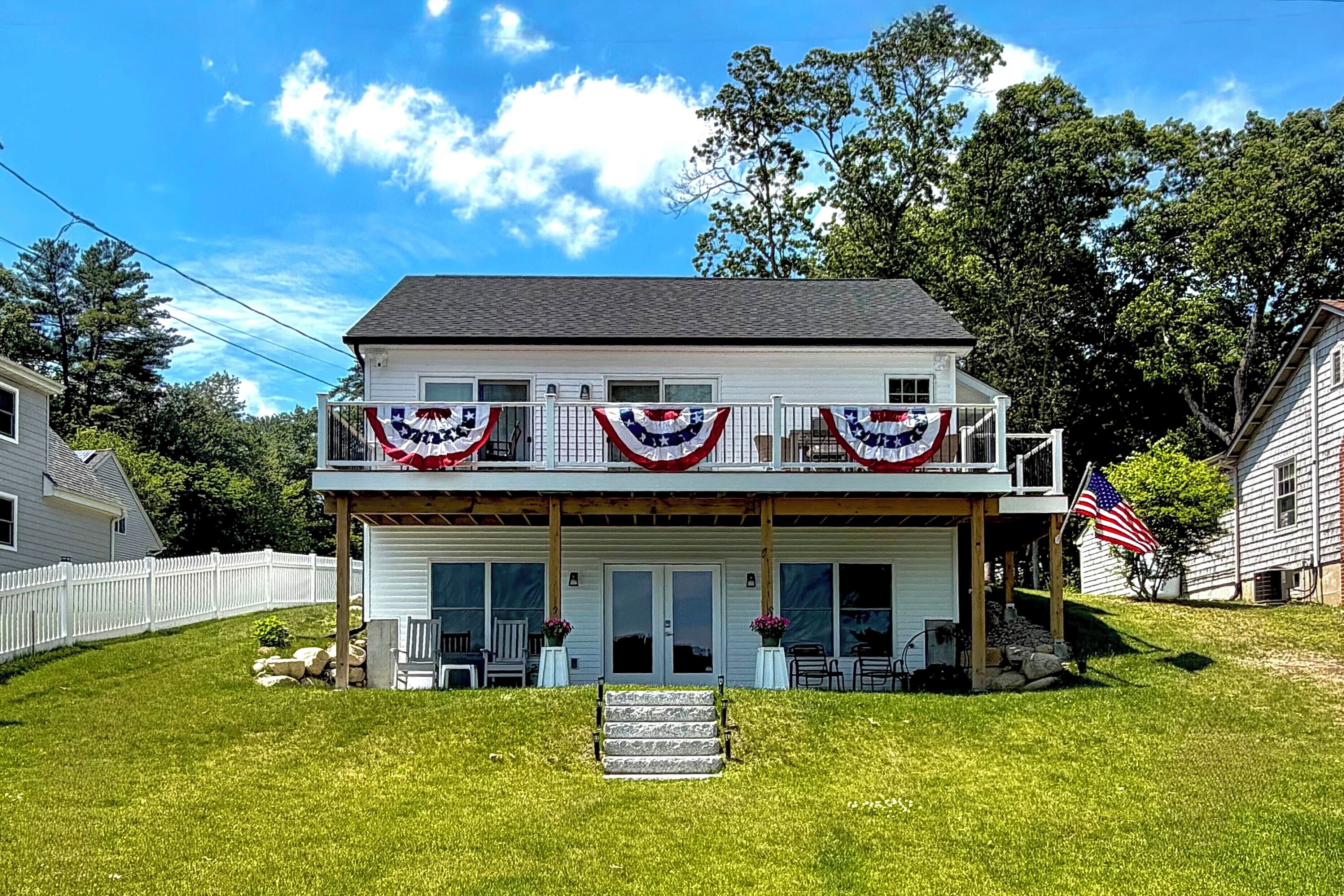 A two-story house with a balcony, a front porch, and a flag.