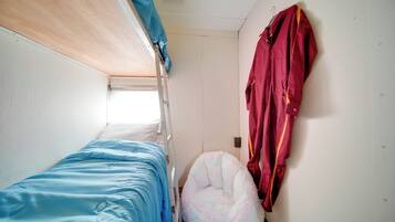 A bunk bed with a blue mattress, a fluffy bean bag chair, and a red jacket hanging on the wall.