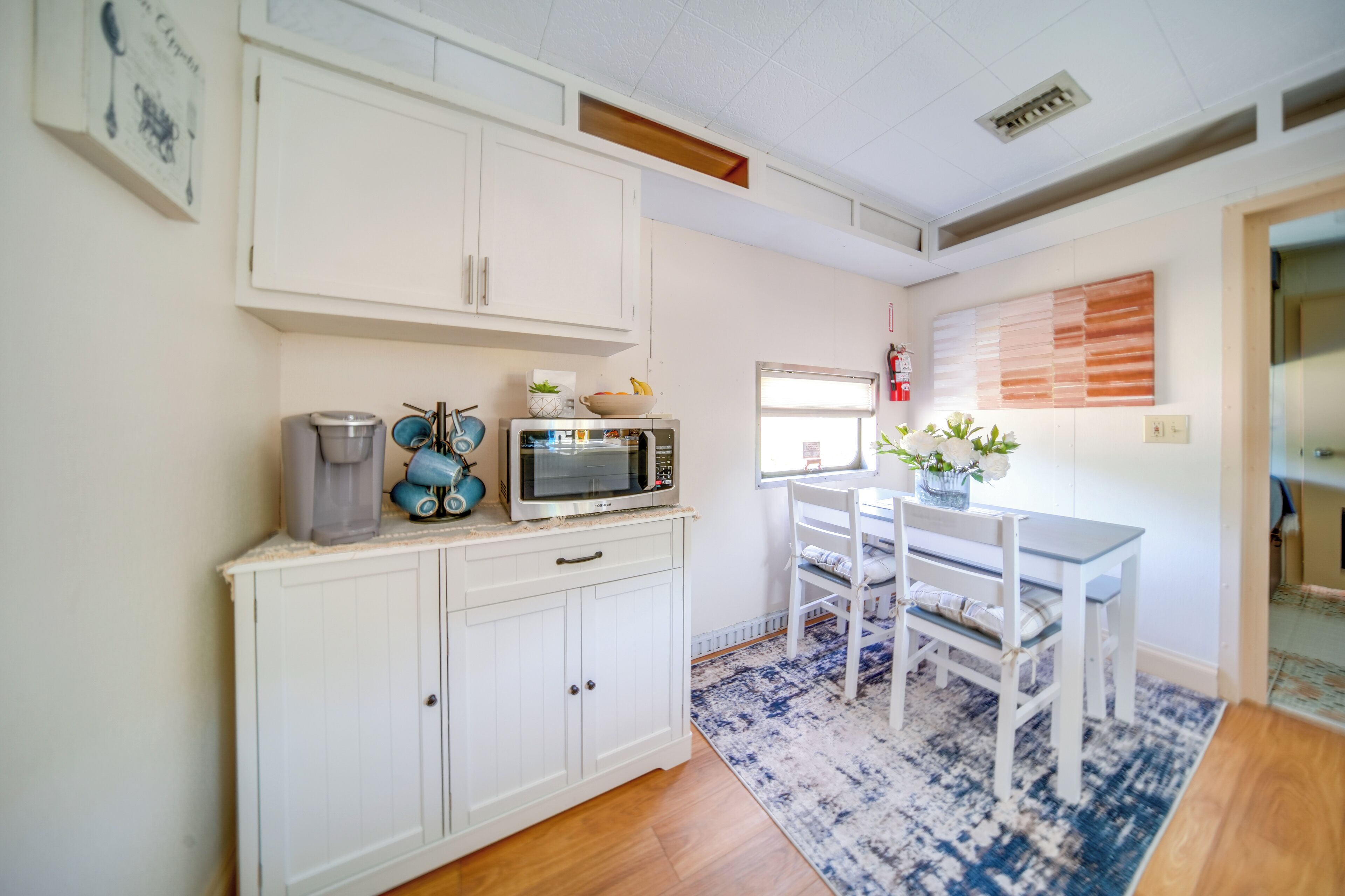 A kitchen with white cabinets, a microwave, and a dining table with chairs.