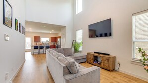 A spacious living area with a grey sectional sofa, a flat-screen TV mounted on the wall, and a wooden cabinet. - Yard & Office: Spacious Family Home in Forney (Forney)