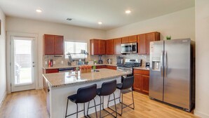 A modern kitchen with wooden cabinets, a stainless steel refrigerator, and a granite countertop. - Yard & Office: Spacious Family Home in Forney (Forney)