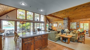 A spacious living area with a large wooden ceiling, a kitchen with wooden cabinets, and a view of the outdoors through large windows. - 6 Mi to Ski Slopes: 'oak View' Lakefront Home! (Speculator)