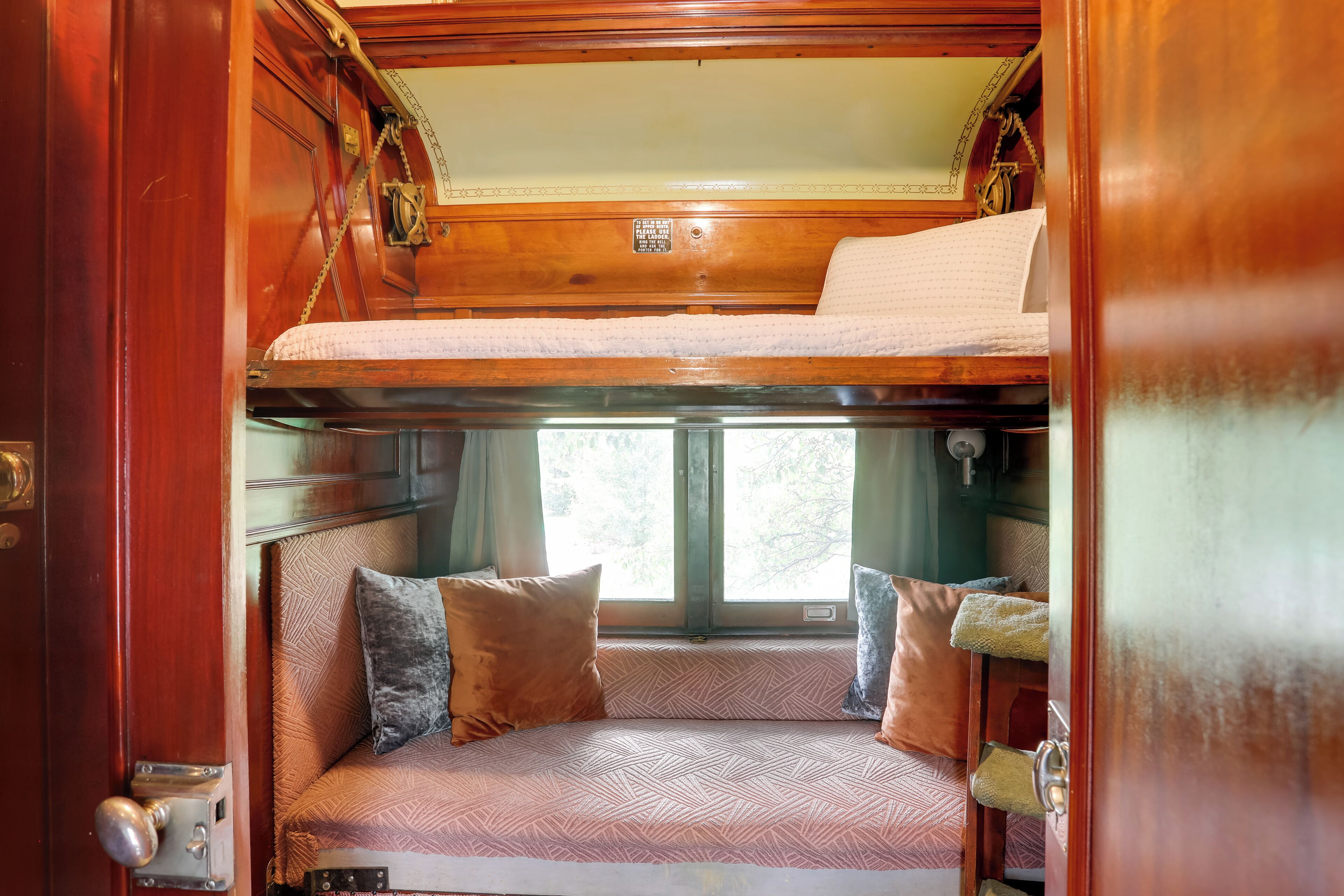 A cozy interior with a bunk bed, cushioned seating, and a window providing natural light.