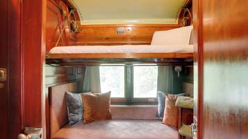 A cozy interior with a bunk bed, cushioned seating, and a window providing natural light.
