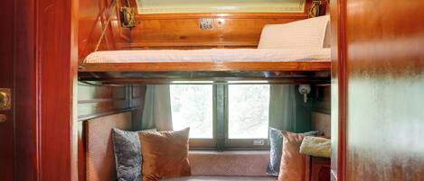 A cozy interior with a bunk bed, cushioned seating, and a window providing natural light.