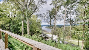 Eine Holzterrasse mit Blick auf einen Fluss und bewaldetes Gebiet.