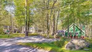 A rustic cabin with a green roof, surrounded by trees and a gravel path. - Featured on Hgtv! Visit This Lottery Dream Home! (Pocono Lake)