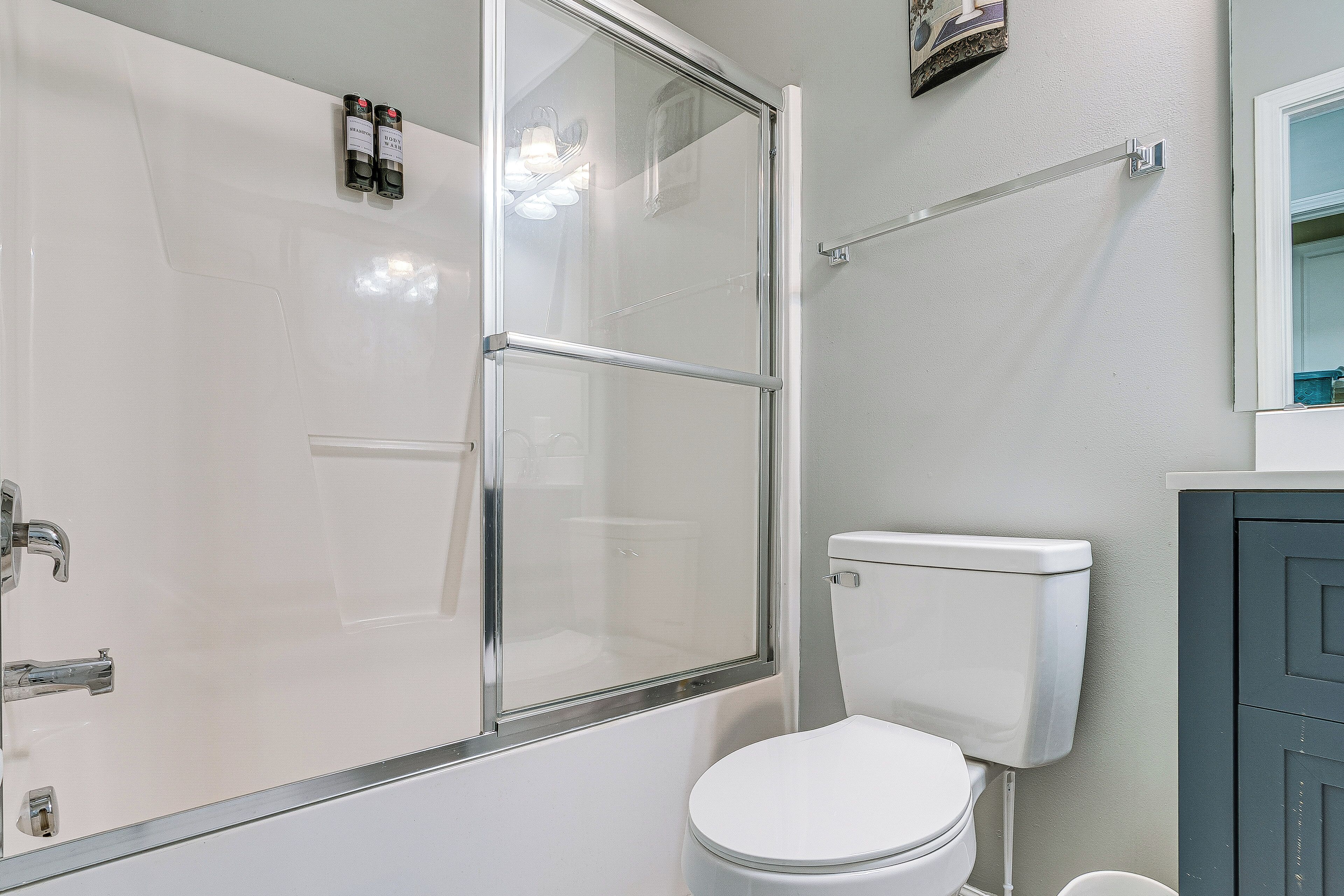 A bathroom with a glass shower enclosure, a white toilet, and a dark-colored cabinet.
