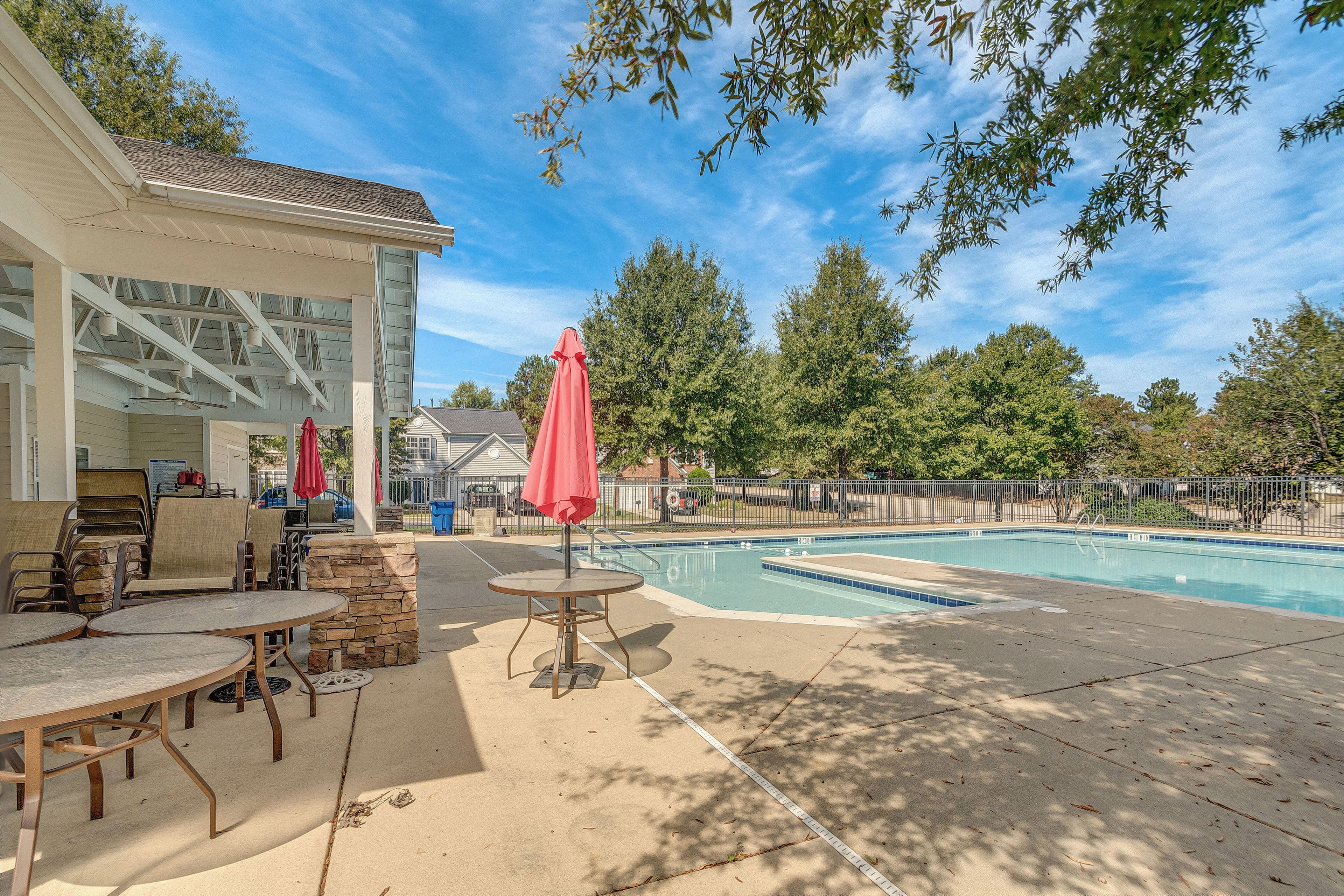 A pool area with a covered patio, outdoor seating, and a stone wall.