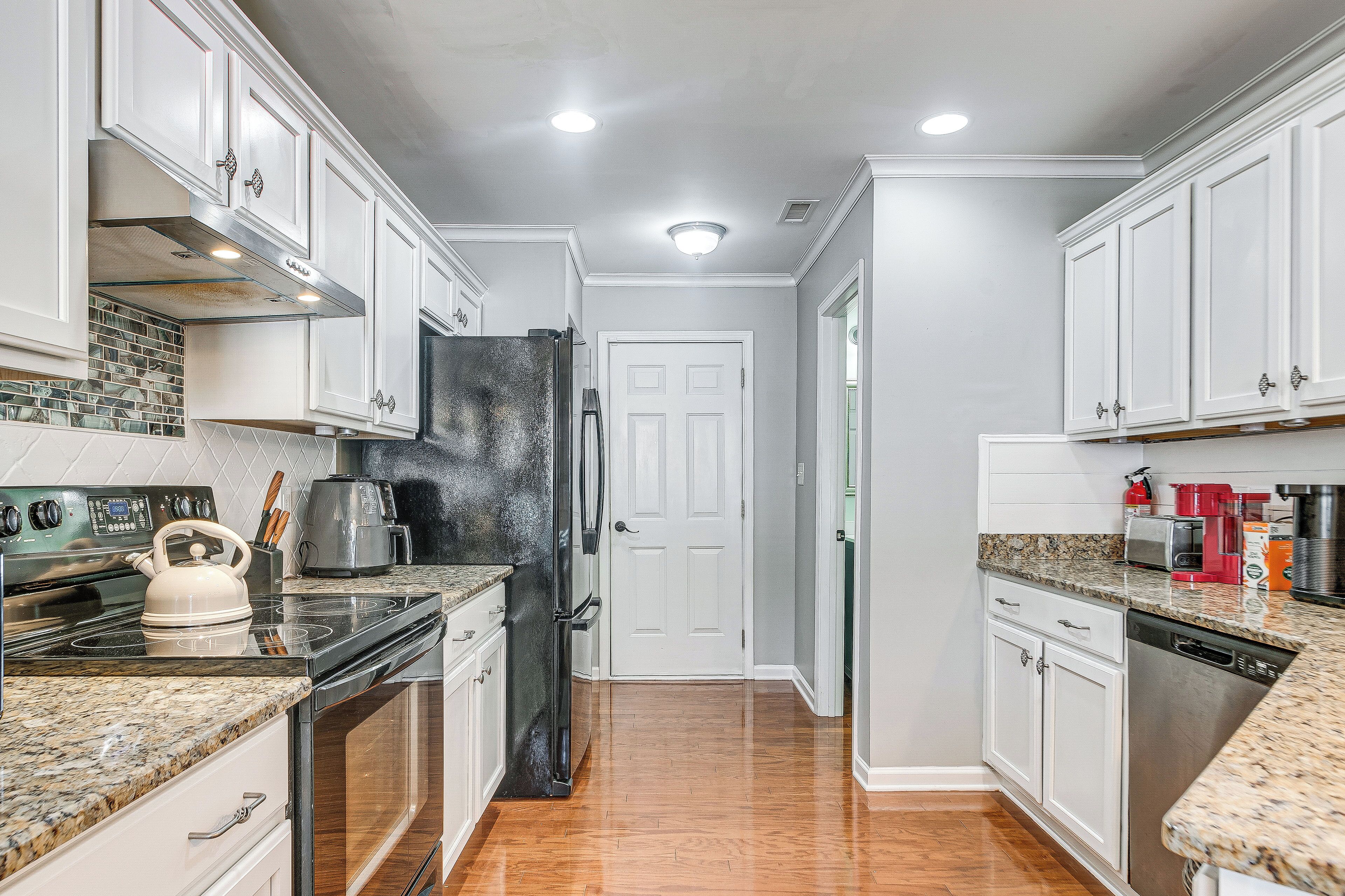 A kitchen with white cabinets, stainless steel appliances, granite countertops, and a tiled backsplash.