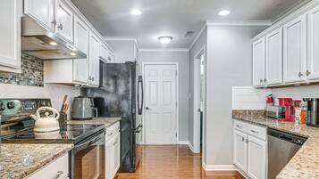 A kitchen with white cabinets, stainless steel appliances, granite countertops, and a tiled backsplash.