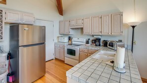 A kitchen with a stainless steel refrigerator, a stove, and a microwave. There are cabinets above the counter and a sink with a paper towel holder. - < 1 Mi to Diamond Peak: Townhome w/ Lake Views (Incline Village)