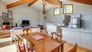 A spacious living area with a wooden dining table, comfortable seating, a stone fireplace, and a kitchen with modern appliances. - < 1 Mi to Diamond Peak: Townhome w/ Lake Views (Incline Village)