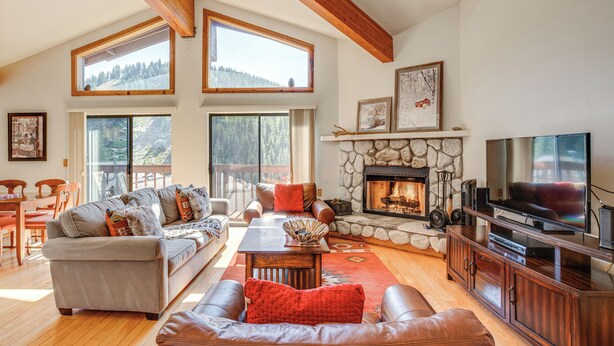 A spacious living room with a fireplace, large windows, and a television. - < 1 Mi to Diamond Peak: Townhome w/ Lake Views (Incline Village)