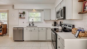 A kitchen with white cabinets, a dishwasher, a stove, and a microwave. - Walk to Campus, FSU Photo Wall: Inviting Retreat! (Tallahassee)