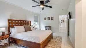 A bedroom with a wooden bed, a ceiling fan, a nightstand, a dresser, and a TV mounted on the wall. - Walk to Campus, FSU Photo Wall: Inviting Retreat! (Tallahassee)