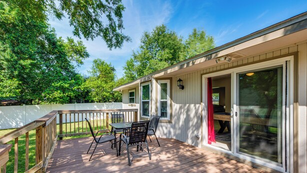 A covered deck with a table and chairs, a sliding glass door, and a white fence. - Walk to Campus, FSU Photo Wall: Inviting Retreat! (Tallahassee)
