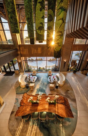 A spacious lobby with a central seating area, a large wooden table, and hanging greenery. - Disney's Polynesian Villas & Bungalows (Lake Buena Vista)