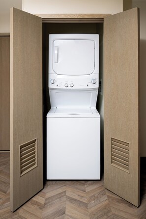 Una unidad compacta de lavadora y secadora integrada, con panel de control y ranuras de ventilación en los laterales.