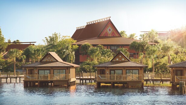 A waterfront hotel with overwater bungalows, a large building with a distinctive roof, and surrounding palm trees. - Disney's Polynesian Villas & Bungalows (Lake Buena Vista)