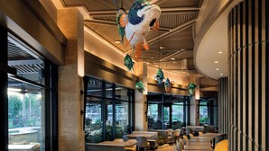 A restaurant interior with high ceilings, hanging fish decorations, and a view of the outdoors through large windows.