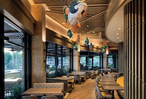 Interior de restaurante con techos altos, decoraciones de peces colgantes y vista al exterior a través de amplios ventanales.